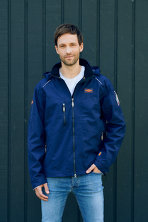 Mann trägt blaue Allwetterjacke von Böckmann  mit herausnehmbarer Kapuze und Stehkragen.